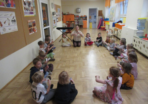 Dzieci siedzą w kole podczas rytmiki.