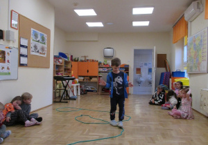 Chłopiec przechodzi po linie ułożonej na podłodze.