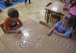 Chłopiec i dziewczynka siedzą przy stoliku i układają rytmy.