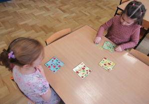 Dziewczynki siedzą przy stoliku i układają warzywne sudoku.