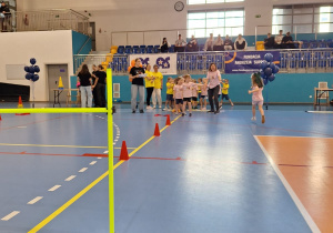 Dzieci stoją w rzędzie podczas olimpiady przedszkolaków.