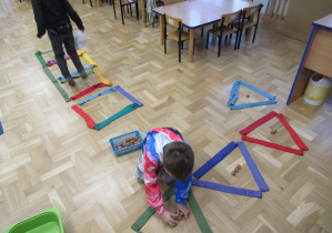 Chłopiec układa orzechy w kształtach ułożonych z szarf.