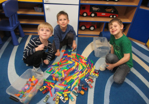 Chłopcy bawią sie na dywanie klockami i samochodzikami.