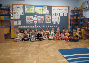 Dzieci pozują do zdjęcia z pluszowymi misiami.