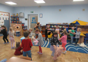 Dzieci tańczą w sali ze swoimi pluszowymi misiami.