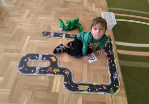 Chłopiec bawi się autem na ulicy ułożonej z puzzli