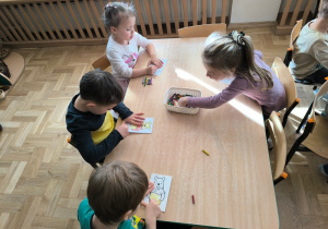 Dzieci kolorują obrazek przedstawiający postać Kubusia Puchatka