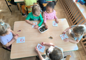 Dzieci kolorują obrazek przedstawiający postać Czerwonego Kapturka