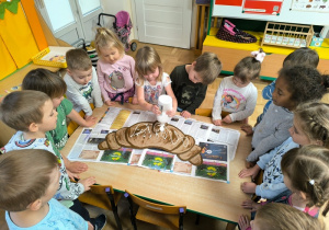 Dzieci ozdabiają świętomarcińskiego rogala wykonanego z tektury