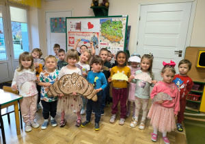 Dzieci trzymają świętomarcińskiego rogala wykonanego z tektury