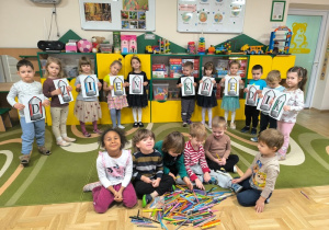 Dzieci siedzą przy rozsypanych kredkach