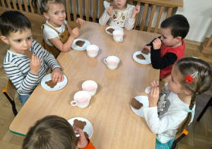 Dzieci jedzą ciasteczka w kształcie misiów