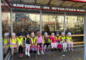 Dziewczynki siedzą na ławce znajdującej się na przystanku autobusowym