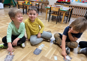 Chłopcy układają obrazki przedstawiające robaczki przy sylwetach jeży