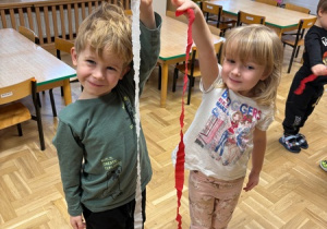 Dzieci trzymają biało-czerwone paski wycięte z krepiny