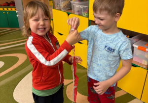 Dzieci trzymają biało-czerwone paski wycięte z krepiny