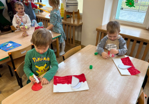 Chłopcy przyklejają biało-czerwone serce do polskich flag