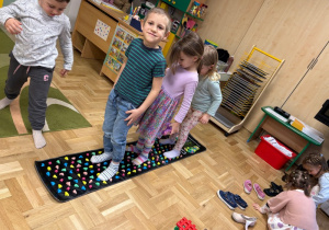 Dzieci spacerują po macie refleksologicznej