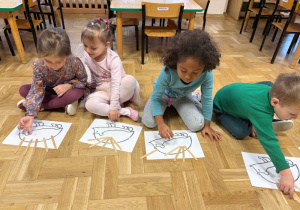 Dzieci układają kolce z drewnianych patyczków na sylwetach przedstawiających jeże