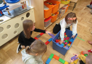 Dziewczynki układają figury geometryczne z klocków.