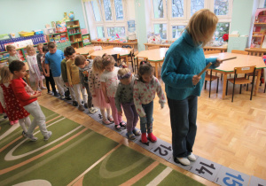 Dzieci stoją na ścieżce liczbowej.