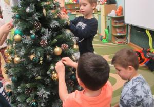 Dzieci ubierają choinkę.