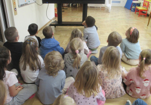 Dzieci siedzą na podłodze i oglądają film o Górnikach.