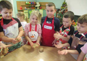 Dzieci ugniatają ciasto na pierniczki.