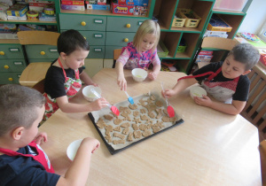 Dzieci smarują pierniczki białkiem.