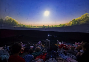 Dzieci leżą podczas seansu w Mikołajkowym Planetarium.