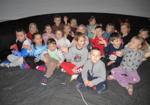 Dzieci siedzą w planetarium.
