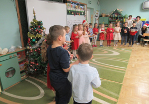 Dzieci stoją w półkolu podczas występu dla rodziców.