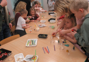 Dzieci z rodzicami siedzą przy stole podczas warsztatów.