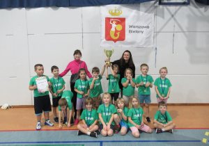 Dzieci pozują do zdjęcia z medalami i pucharem.