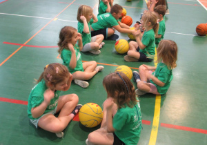 Dzieci ćwiczą w parach podczas zajęć z koszykówki.