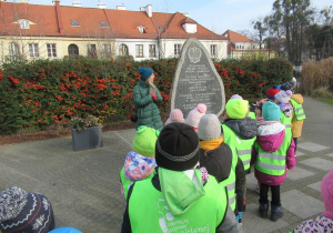 Dzieci stoją przed kamiennym pomnikiem.