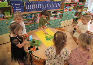 Dzieci wykonują wspólną prace plastyczną.