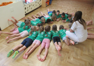 Dzieci leżą na podłodze tworząc koło.