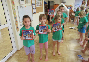 Dzieci pozują do zdjęcia z książeczkami otrzymanymi na zajęciach z elementami teakwondo.