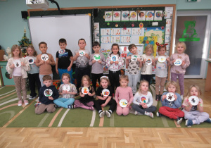 Dzieci pozują do zdjęcia z wykonanymi samodzielnie pracami plastycznymi.