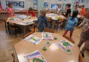 Dzieci malują farbami choinki.