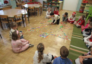 Dzieci siedzą w kole, przed nimi choinka ułożona z klocków.