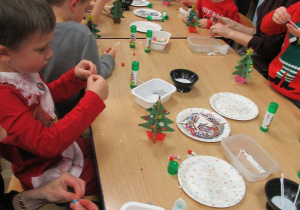 Dzieci z rodzicami podczas warsztatów świątecznych pracują przy stole