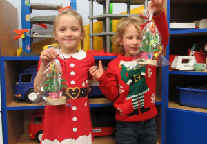 Dziewczynka i chłopiec prezentują wykonane podczas warsztatów prace.