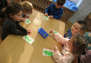 Dzieci przy stoliku wykonują prace plastyczne - choinki wyklejane plasteliną.