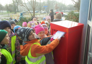 Dzieci wrzucają listy do Świętego Mikołaja do skrzynki.