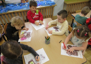 Dzieci przy stoliku kolorują.