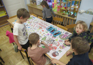 Dzieci wspólnie kolorują dużą świąteczną kolorowankę.