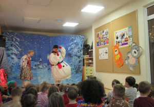 Dzieci siedzą na podłodze, przed nimi bałwanek i góralka.