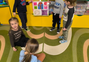 Dzieci trzymają plakat przedstawiajacy kwadraty